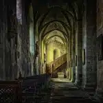 Libro aperto su tavolo in chiostro antico con luce naturale autunnale