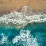 Spiaggia affollata vista dall'alto con ombrelloni e bagnanti fitti lungo la battigia