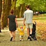 Gruppo di persone che camminano insieme in un parco con alberi, una persona fa stretching