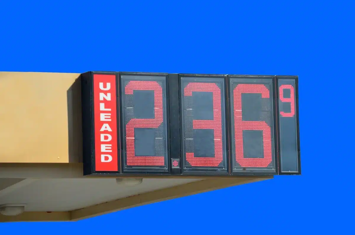 Cartellone dei prezzi del carburante e pompe con auto in sosta