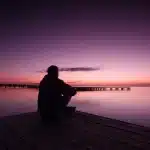 Coppia in silhouette che passeggia sul lungolago al tramonto con sculture e alberi sullo sfondo
