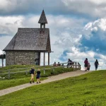Interno di una canonica di montagna con opere d'arte esposte su pareti in pietra