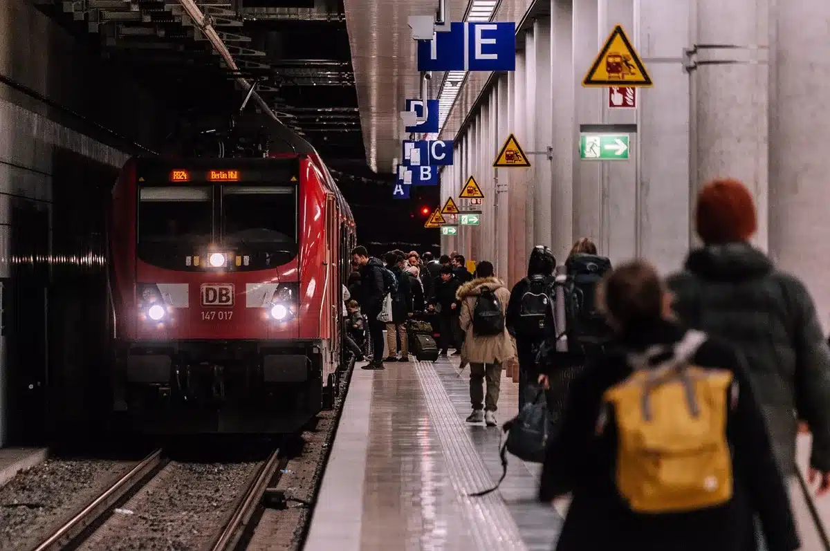 Passeggeri in attesa su un binario ferroviario con tabellone partenze bloccato