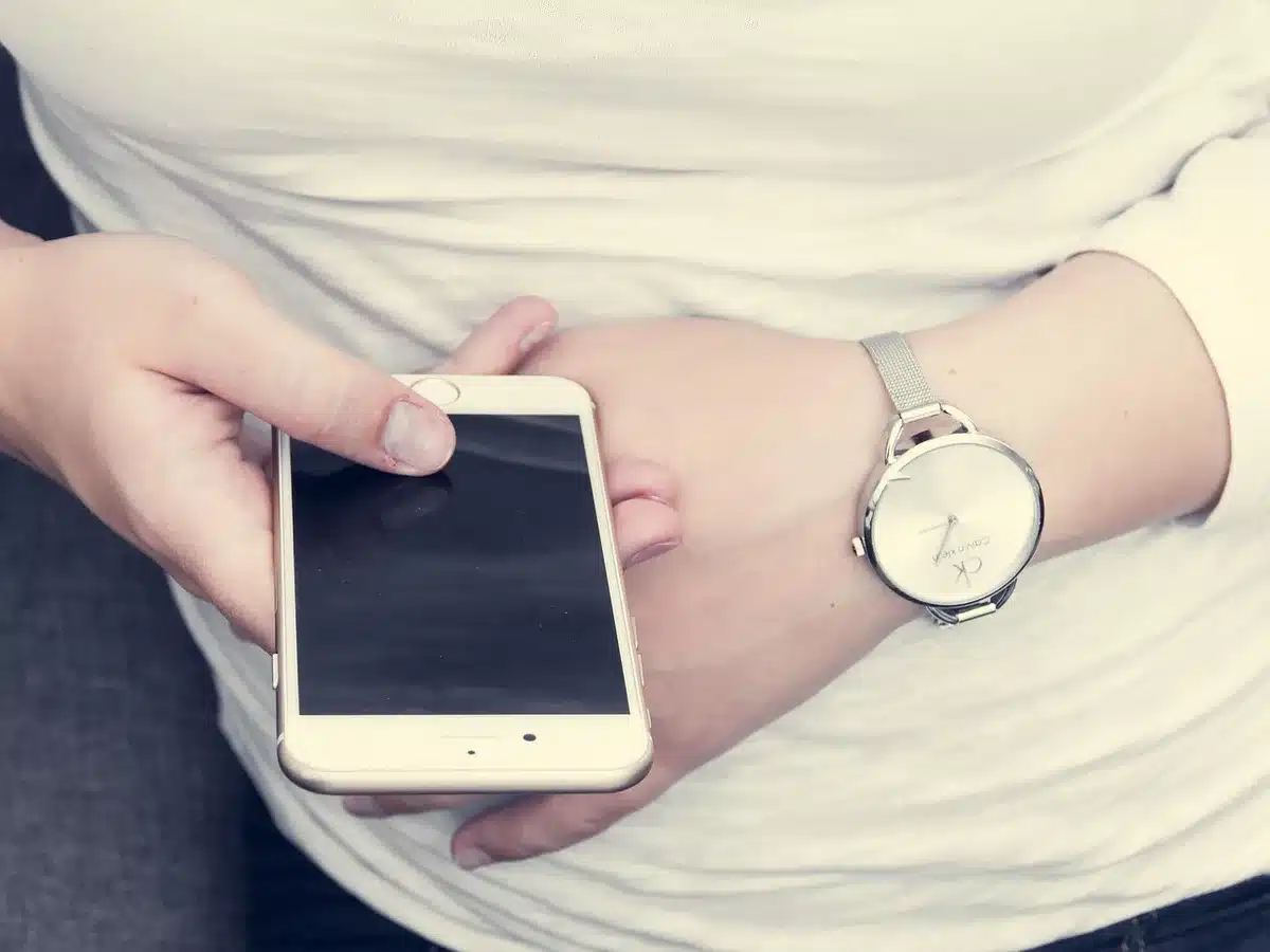 Giovane donna che guarda lo schermo del telefono mentre scrive messaggi