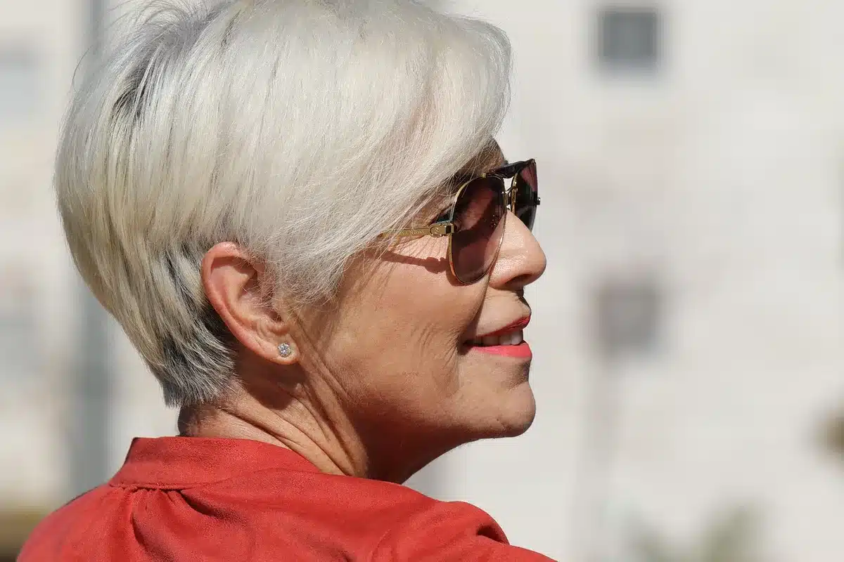 Donna che si osserva allo specchio con caschetto corto in momento di riflessione
