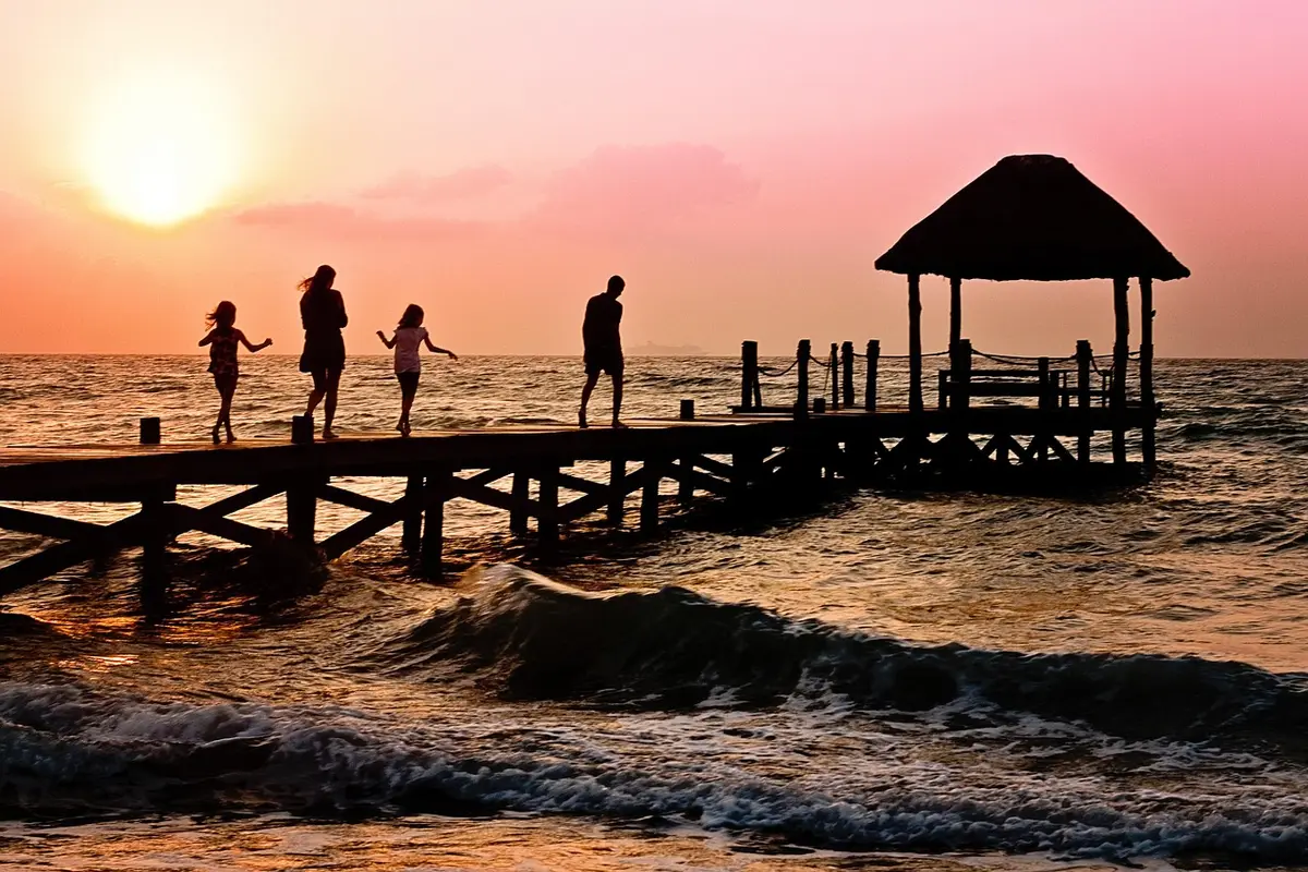 Famiglia che passeggia lungo la spiaggia al tramonto