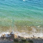 Tramonto dorato sulla costa adriatica delle Marche con figure silhouettate in spiaggia