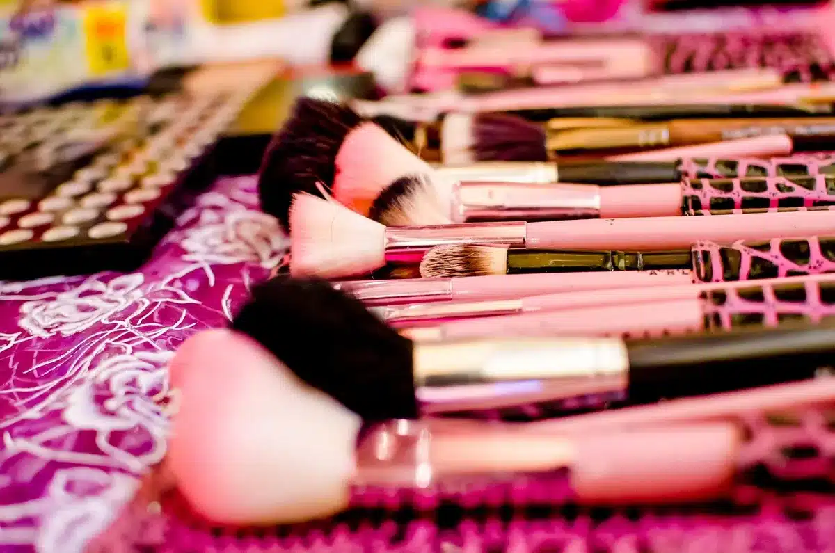 Mani che applicano illuminante e contour su una pelle viso anonima