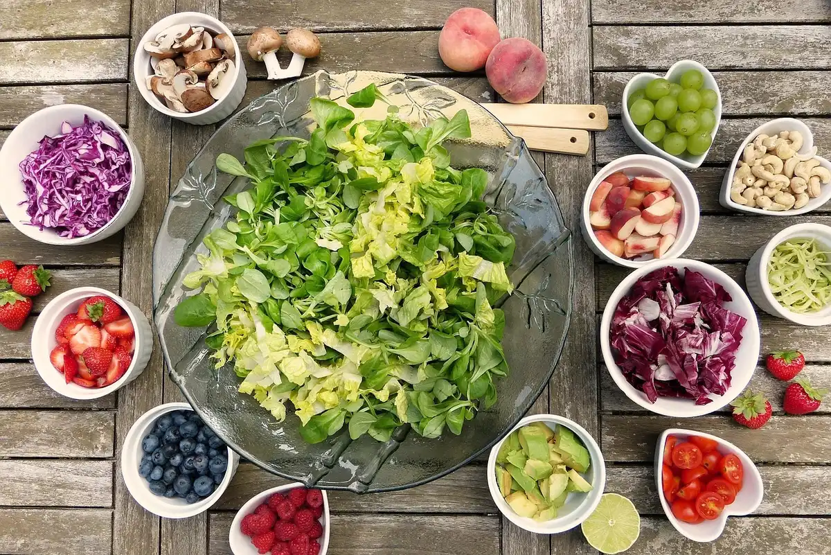 Buffet estivo con verdure, insalate e piatti proteici disposti su tavolo