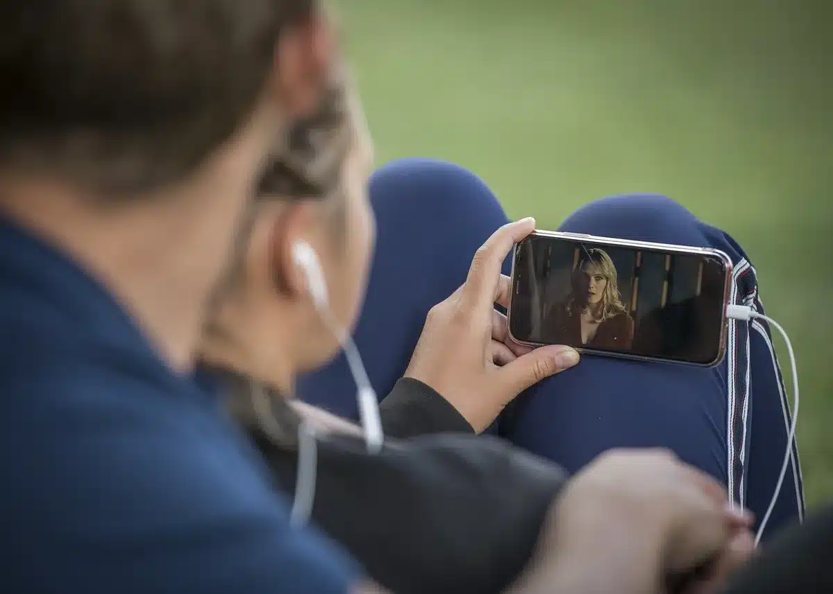 Mano che tiene uno smartphone con profili social visibili
