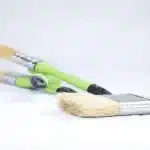 Mani anonime che lavorano su un banco con attrezzi e materiali per fai-da-te