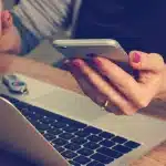 Silhouette al telefono davanti a un portatile con schermata di trasferimenti e una cartella generica