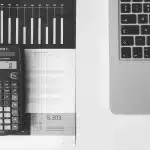 Mani anonime su documenti finanziari e calcolatrice in un ufficio luminoso