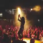 Silhouette di fan davanti a un palco vuoto in arena con luci calde