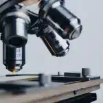 Bancone di laboratorio con provette, micropipetta e microscopio sfocato
