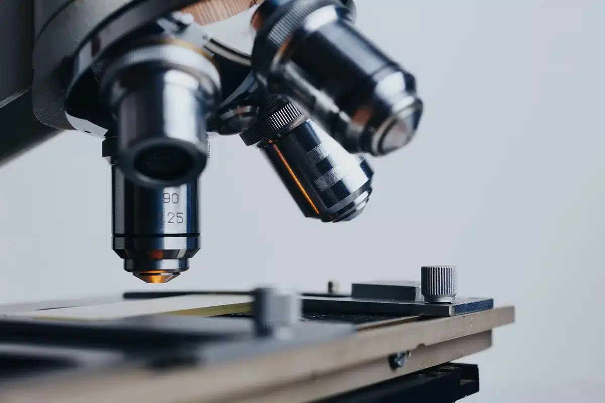 Bancone di laboratorio con provette, micropipetta e microscopio sfocato