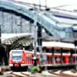 Valigia vintage e giornale piegato su una panchina in una stazione vuota, luce naturale