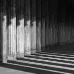 Chiostro antico con archi in pietra e panche vuote in luce mattutina