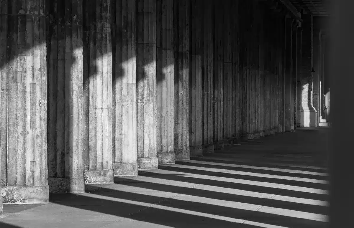 Chiostro antico con archi in pietra e panche vuote in luce mattutina