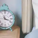 Camera da letto ordinata con lampada al comodino e orologio, luce calda serale