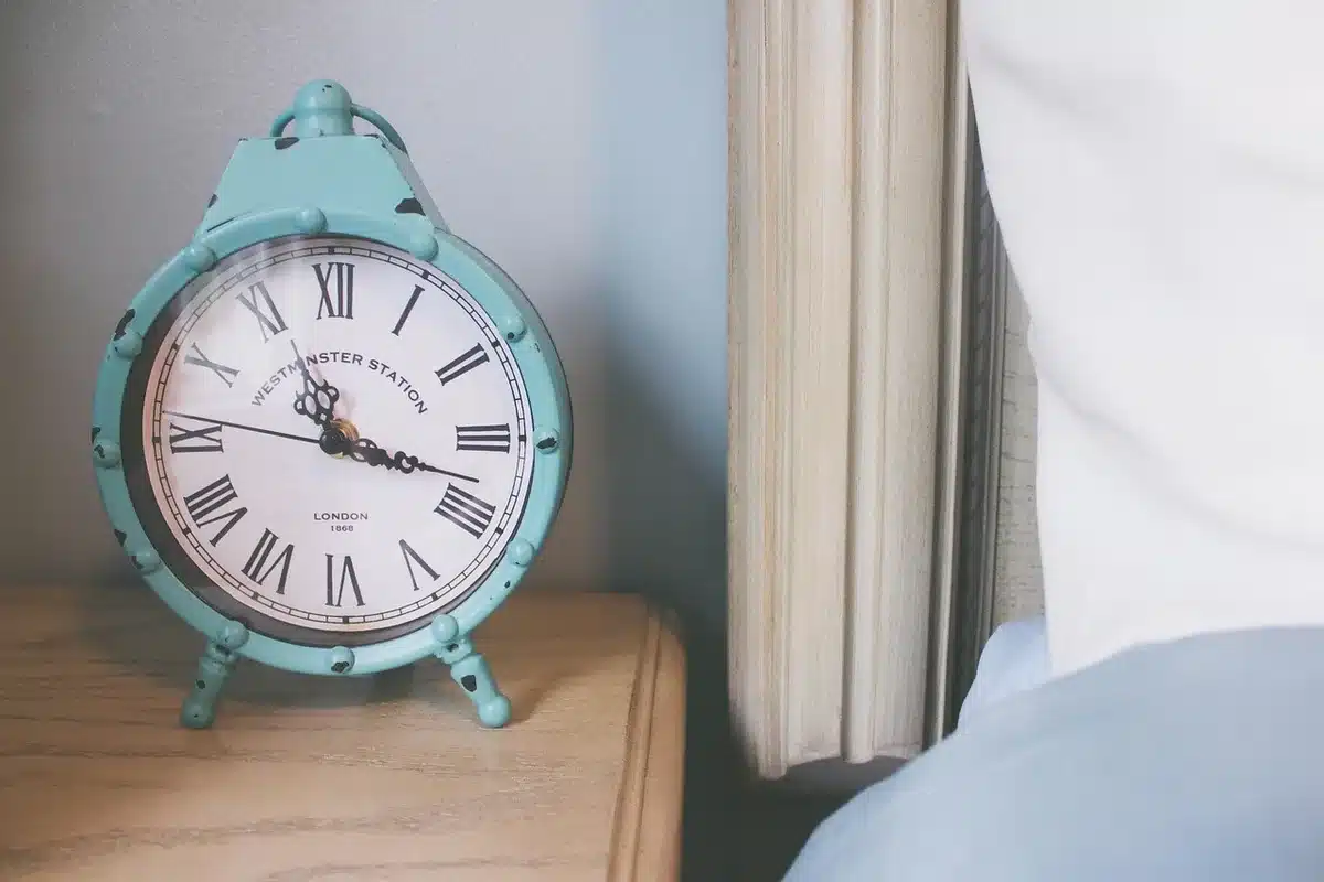 Camera da letto ordinata con lampada al comodino e orologio, luce calda serale